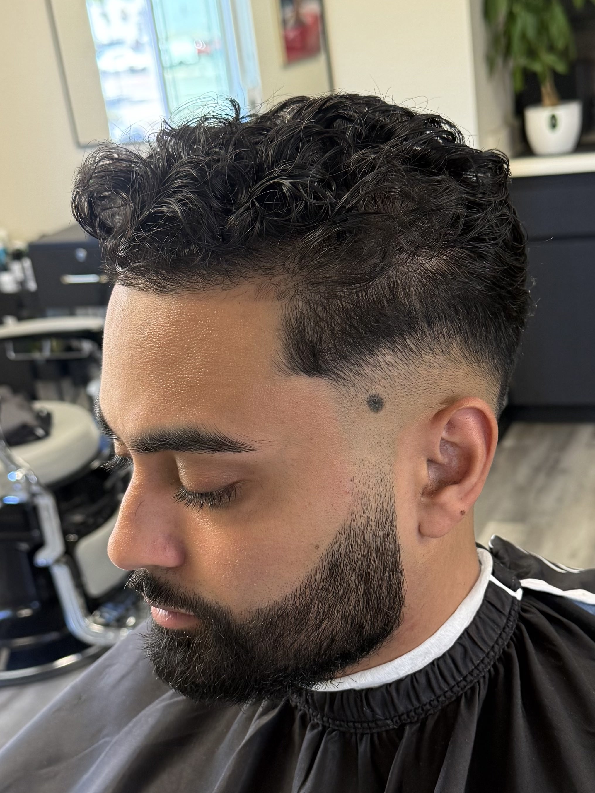 Curly top with low taper fade and beard lineup by Javistylz